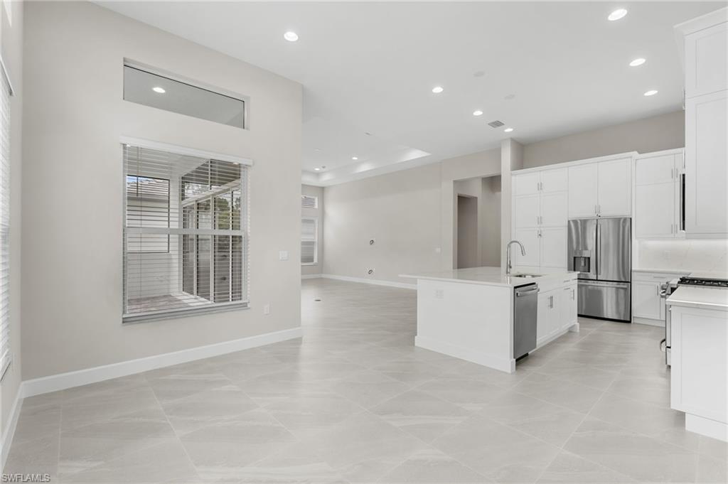 Open-concept living space featuring high ceilings with recessed lighting, large format tile flooring, and a contemporary kitchen