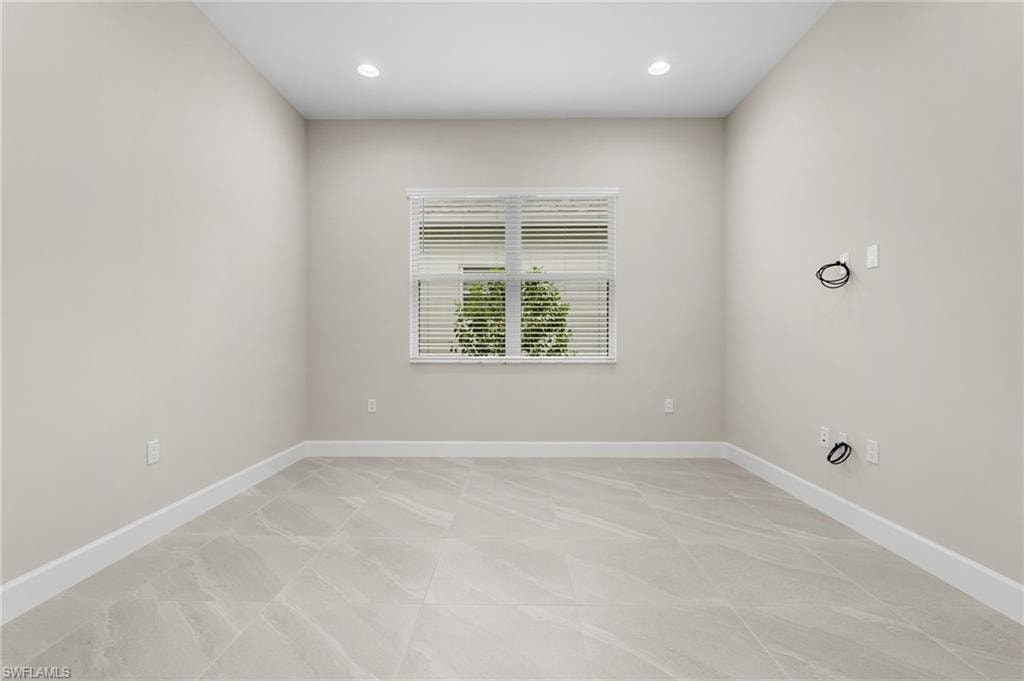 Spacious den area featuring light-toned walls, contemporary recessed lighting, and large format tile flooring
