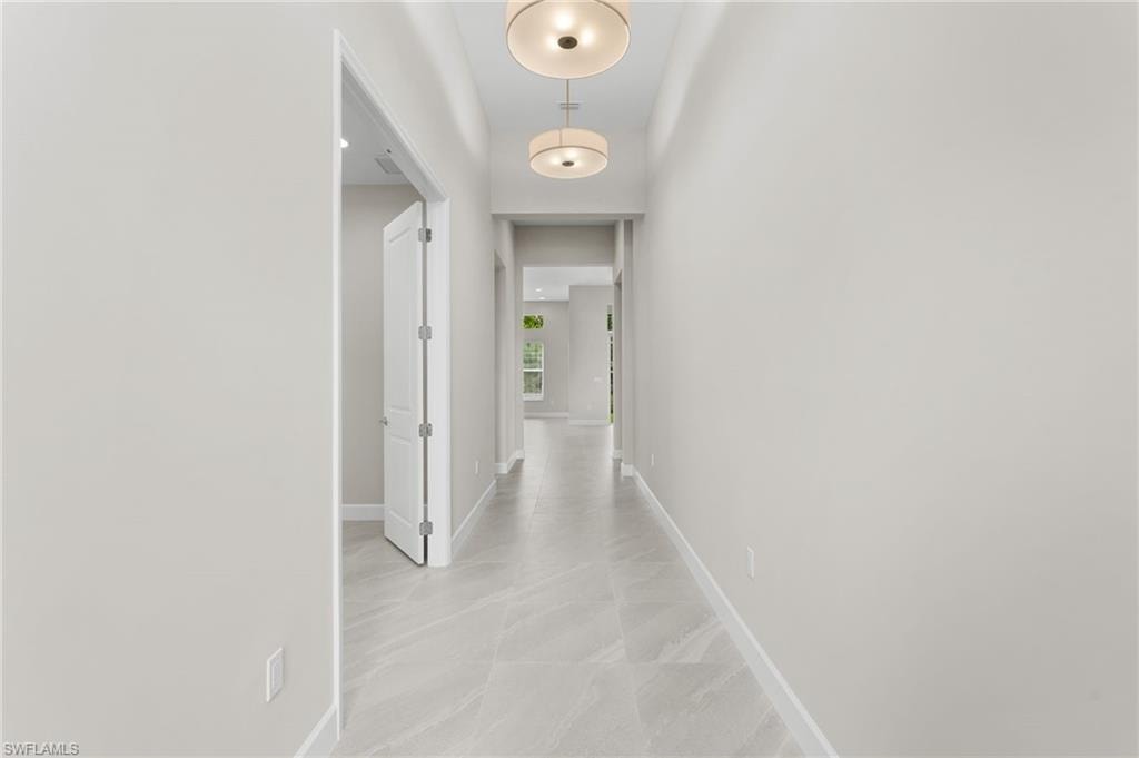 Long foyer hallway featuring light-toned walls, 24" x 24" procelain tile flooring with subtle veining, and contemporary flush mount lighting fixtures