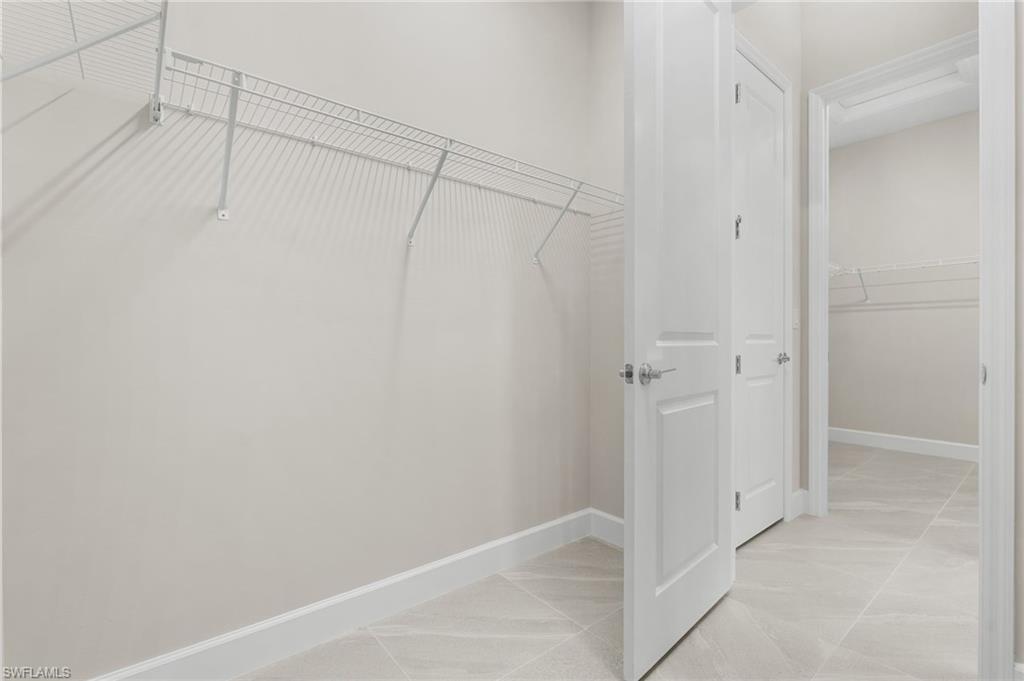 2 master walk-in closets featuring wire shelving, white baseboards, and light-toned tile flooring