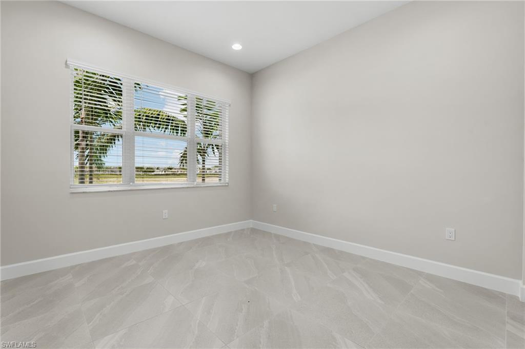 Guest bedroom with large window with white blinds, recessed lighting, light gray walls, white baseboards, and gray marble-look tile flooring