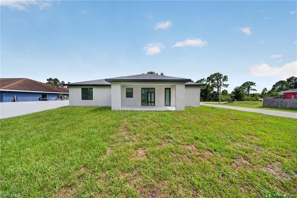 Rear exterior featuring a white stucco finish, dark-framed windows, and a covered patio area