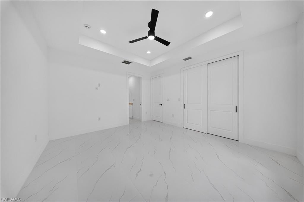 Spacious room featuring white walls and large format tile flooring