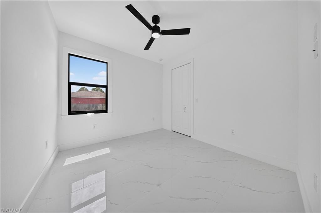 Bright interior space featuring large format tile flooring, a contemporary black ceiling fan, and a single window with black trim