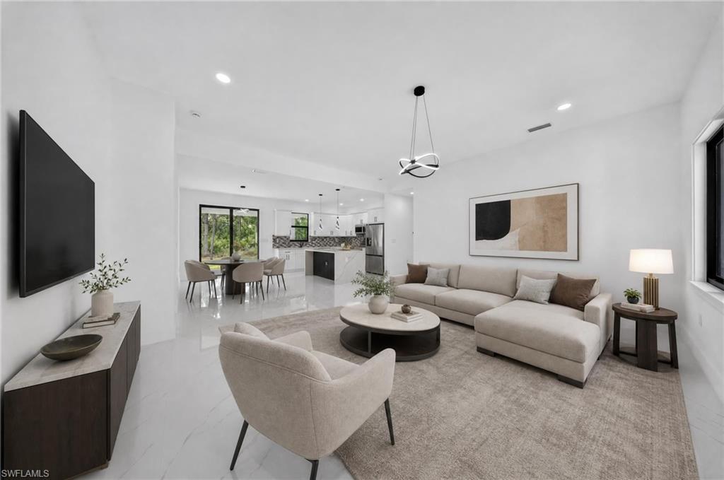 Open-concept living space featuring high ceilings, recessed lighting, and large format tile flooring