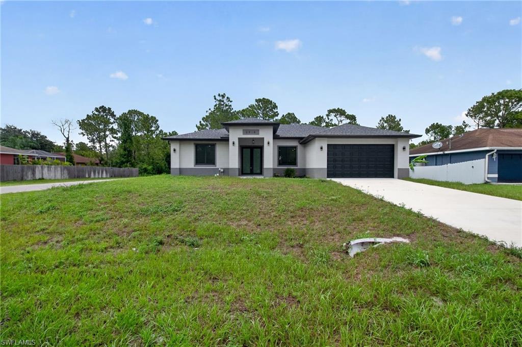 Contemporary stucco exterior with a dark gray two-car garage door, coordinating dark gray window frames, and a concrete driveway