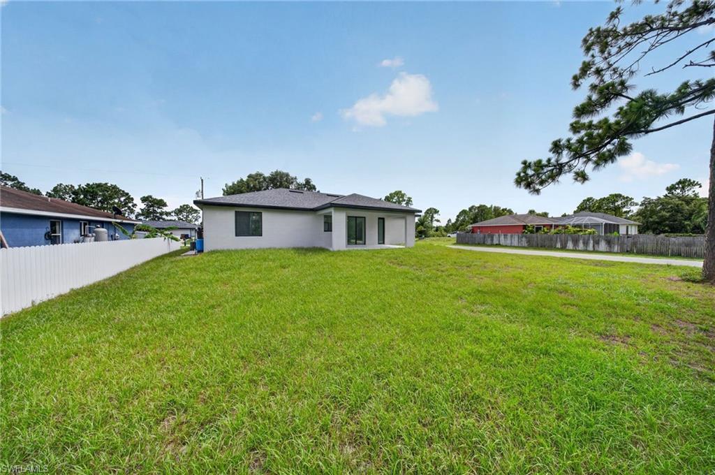 Spacious backyard featuring a manicured lawn, a white privacy fence, and a modern exterior with dark-framed windows