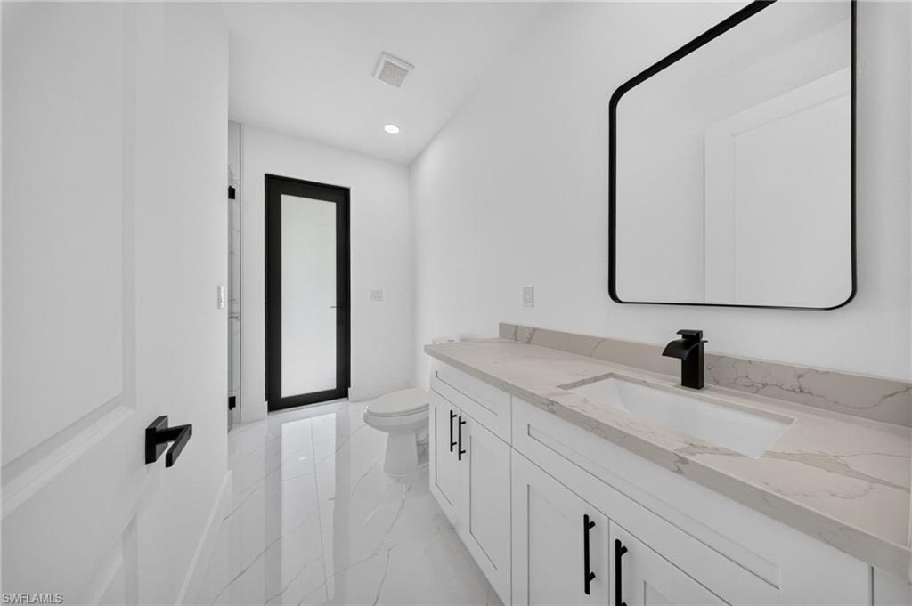 Modern bathroom featuring a white vanity with an integrated sink, a light-toned countertop with subtle veining, and a contemporary matte black faucet