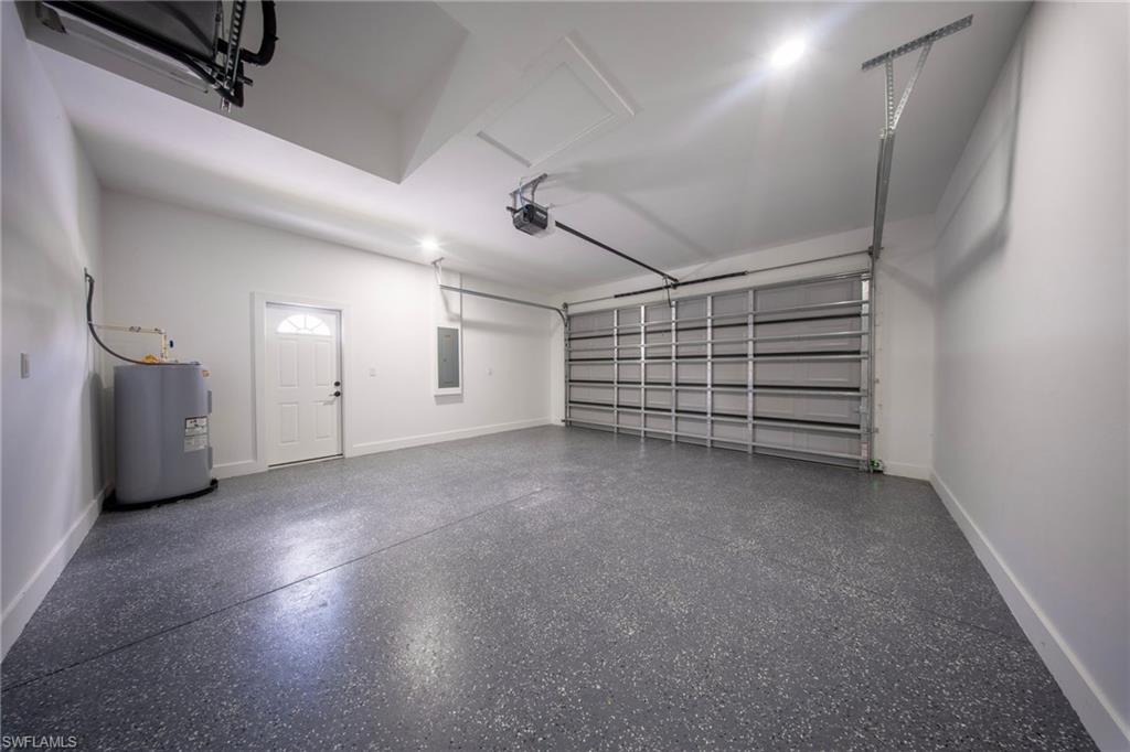Spacious garage featuring a durable speckled epoxy floor, white interior walls, and an automatic garage door opener