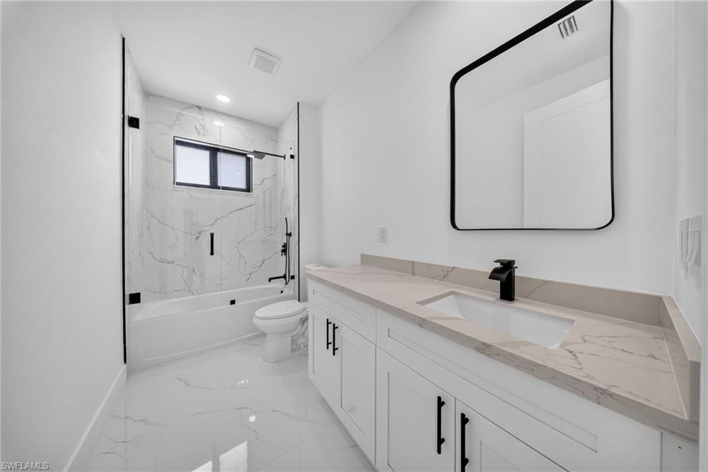 Bathroom featuring a white vanity with a stone-finish countertop, integrated sink, and matte black faucet