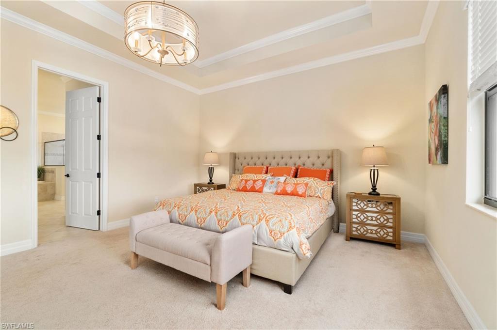 Carpeted room featuring a double tray ceiling with crown molding, a decorative chandelier, and a panel door