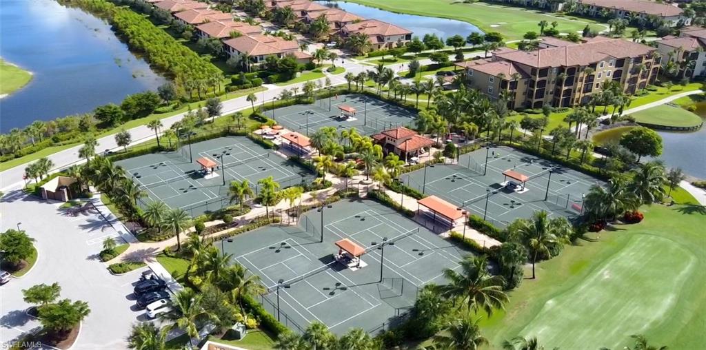 Multiple tennis courts surrounded by lush landscaping and palm trees