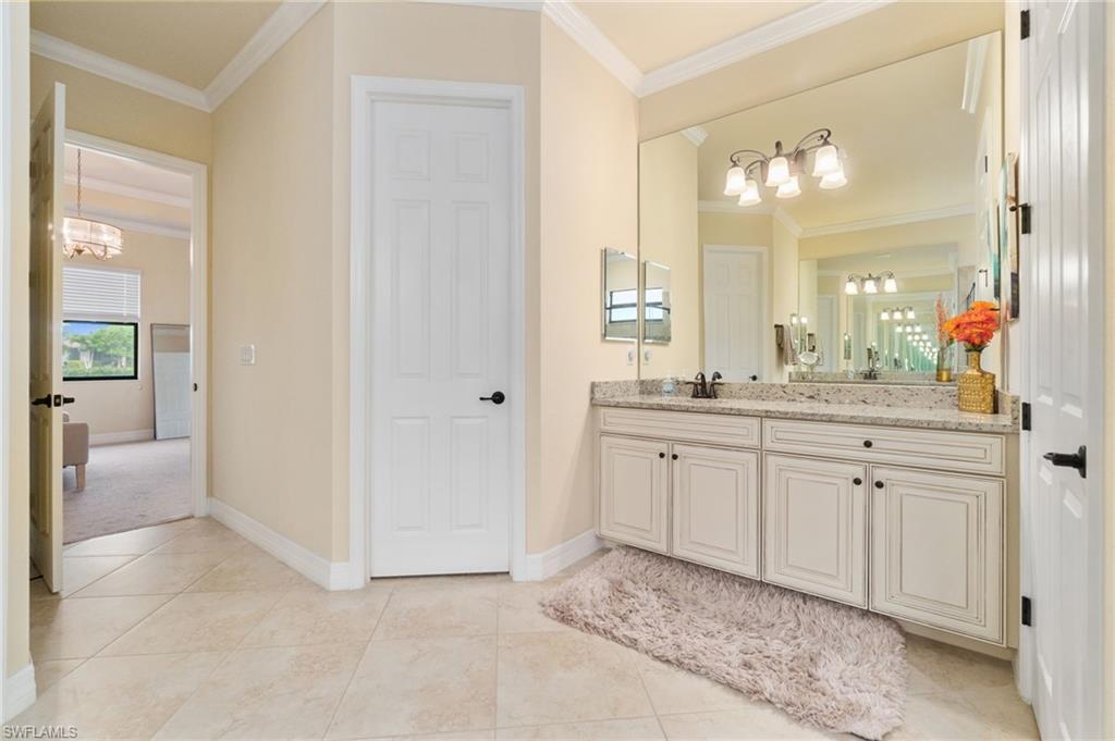 Dual sink vanity featuring a light-toned countertop, white cabinetry with black hardware, and an expansive mirror
