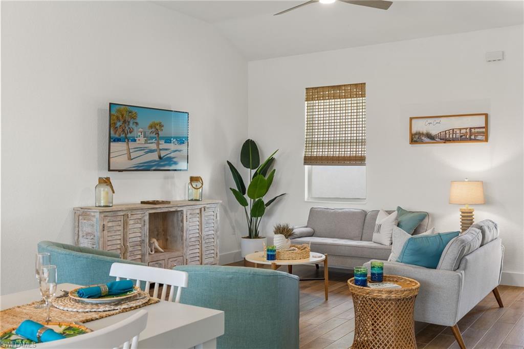 Living room featuring wood finished floors, a ceiling fan, and vaulted ceiling