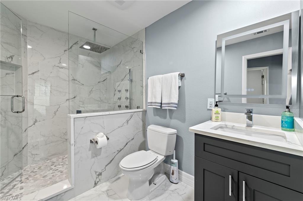 Bathroom with tile patterned flooring, an enclosed shower, vanity, and toilet