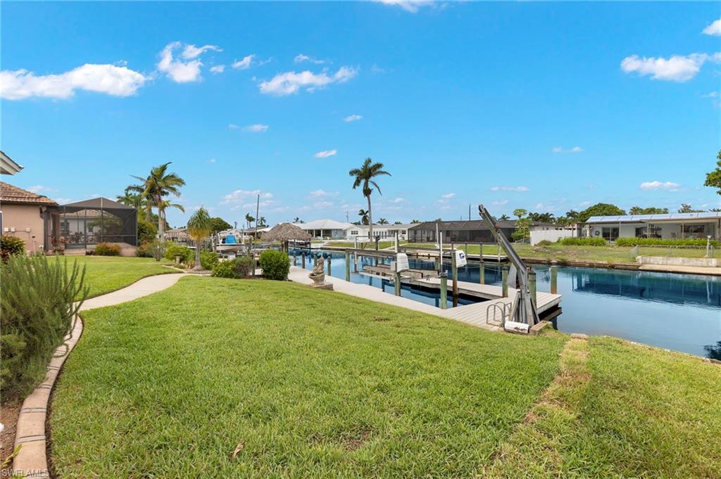 View of dock with a yard and a water view