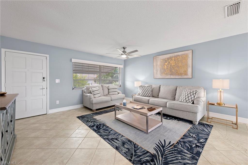 Tiled living room featuring ceiling fan and a textured ceiling