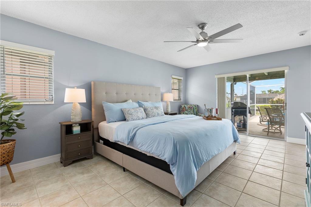 Bedroom featuring a textured ceiling, ceiling fan, access to exterior, and light tile patterned floors