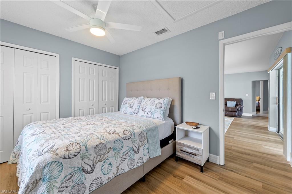 Bedroom featuring ceiling fan, two closets, and light hardwood / wood-style flooring