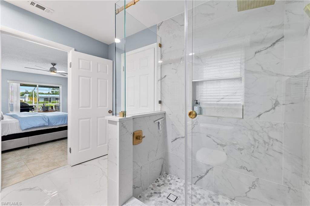 Bathroom featuring ceiling fan, tiled shower, and tile patterned floors