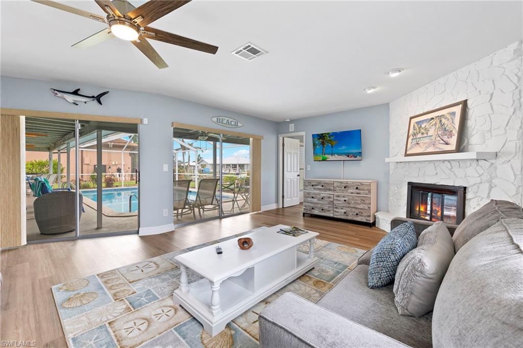 Living room with hardwood / wood-style floors, ceiling fan, and a fireplace