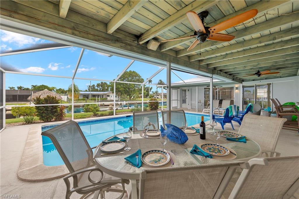 View of pool featuring glass enclosure, a patio area, and ceiling fan