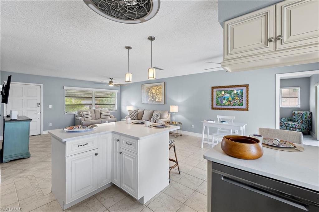 Kitchen with a textured ceiling, ceiling fan, light tile patterned flooring, and hanging light fixtures