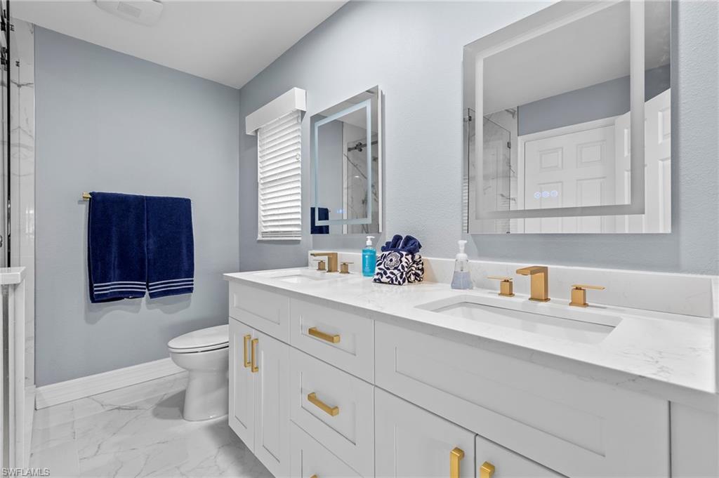 Bathroom featuring tile patterned floors, an enclosed shower, vanity, and toilet