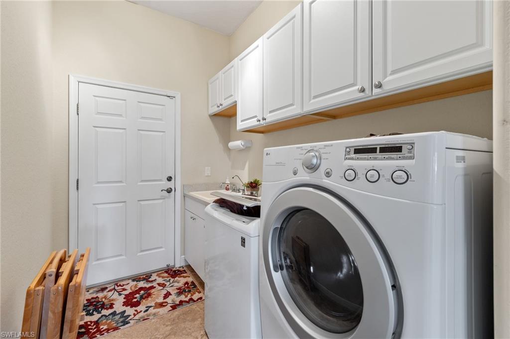 Washroom with sink, cabinets, washer and clothes dryer.