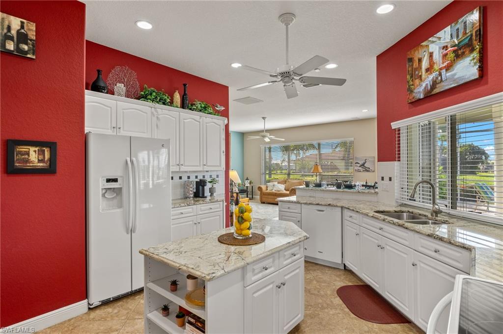 Kitchen featuring white cabinetry, white appliances, light tile patterned floors, ceiling fan, and sink