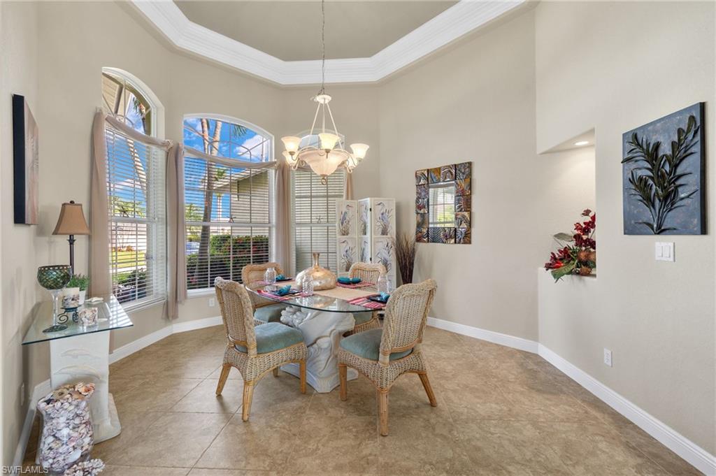 Dining area featuring a tray ceiling, an inviting chandelier, light tile patterned floors, and a high ceiling