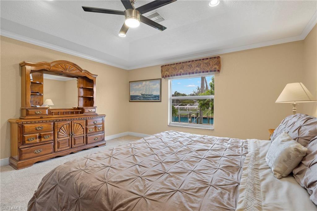 Bedroom featuring carpet, crown molding, ceiling fan, and a tray ceiling