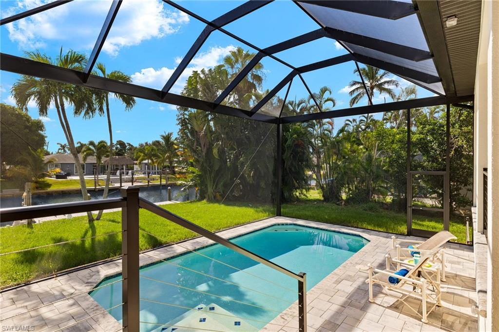 View of pool featuring a lanai, a water view, a lawn, and a patio