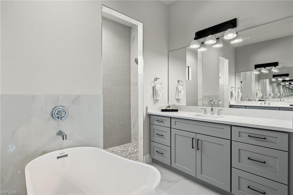 Bathroom with tile walls, separate shower and tub, and vanity