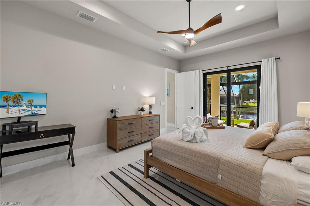 Bedroom featuring a tray ceiling, access to outside, and ceiling fan
