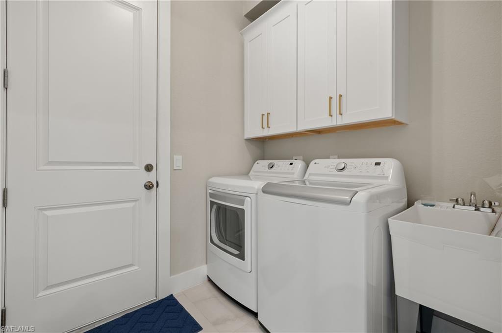 Washroom featuring light tile patterned floors, separate washer and dryer, cabinets, and sink