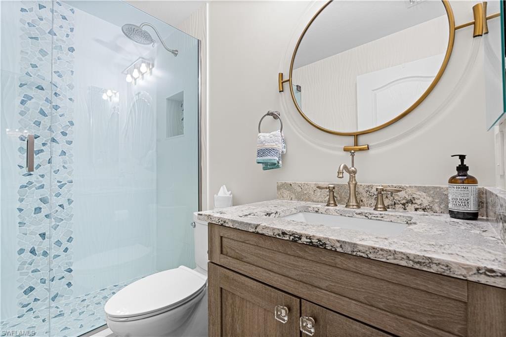 Contemporary bathroom featuring a frameless glass shower enclosure with decorative tile inlay, a rainfall showerhead, and a built-in shower niche