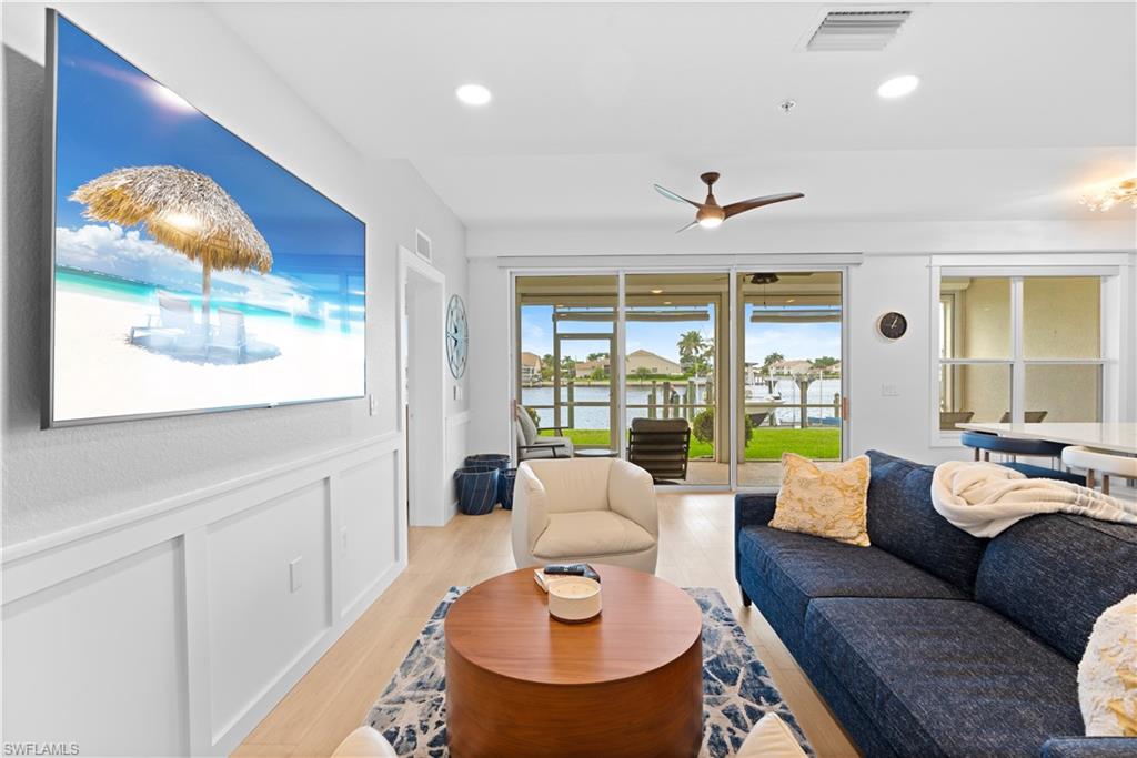 Living area featuring light wood-finish flooring, white paneled accent wall, recessed lighting, and a contemporary ceiling fan