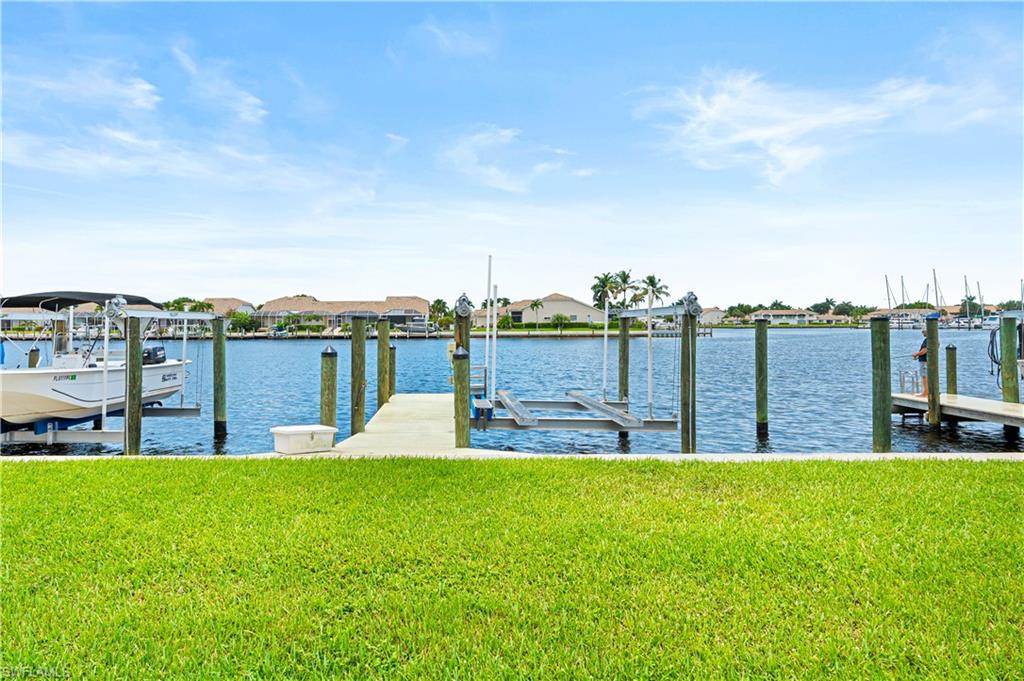 Waterfront property featuring a private boat dock, boat lift, and manicured lawn