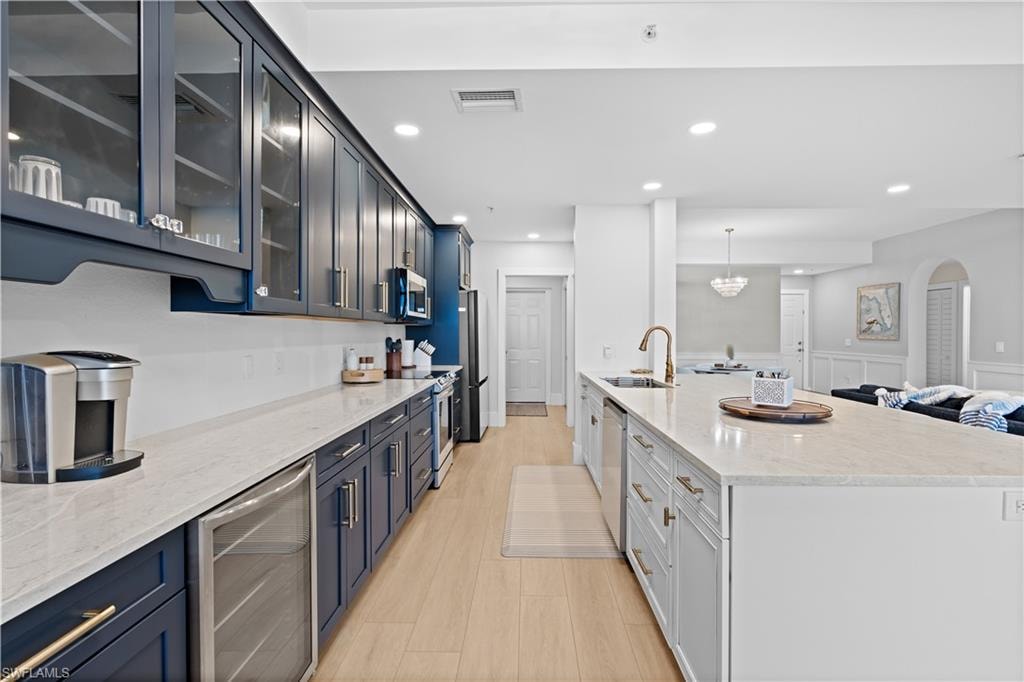 Modern kitchen featuring dark blue cabinetry, light wood-finish flooring, and light-toned countertops