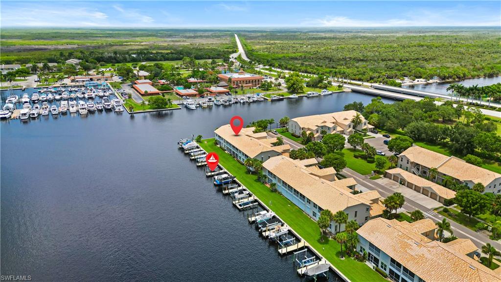 Waterfront development featuring multiple buildings with terracotta-style roofs, private boat docks, and manicured green spaces
