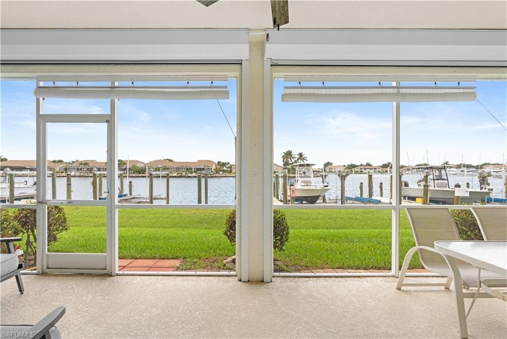 Screened patio with a textured concrete floor, overlooking a manicured lawn and waterway with boat docks
