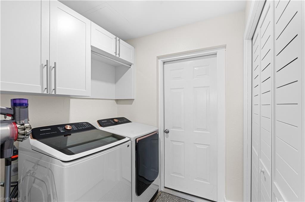 Laundry area featuring white cabinetry with silver hardware, an integrated hanging rod, and louvered bi-fold doors