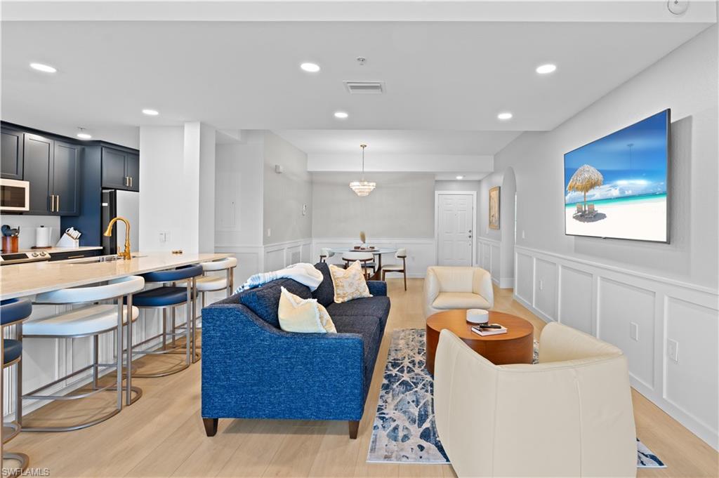Open-concept living area with light wood-finish flooring, recessed lighting, and wainscoting details