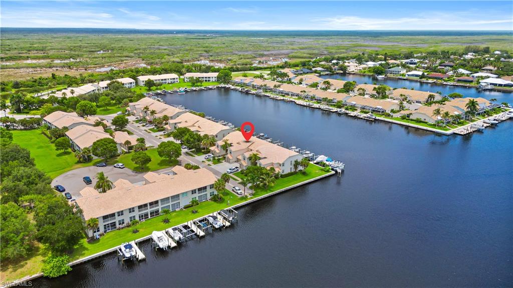 Waterfront community with direct canal access, featuring established landscaping, multiple boat slips, and a serene marshland backdrop
