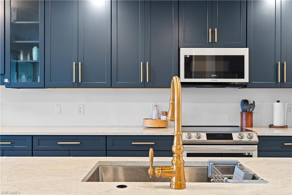Kitchen featuring abundant blue cabinetry with gold-tone hardware, a stainless steel undermount sink, and a gold-tone gooseneck faucet