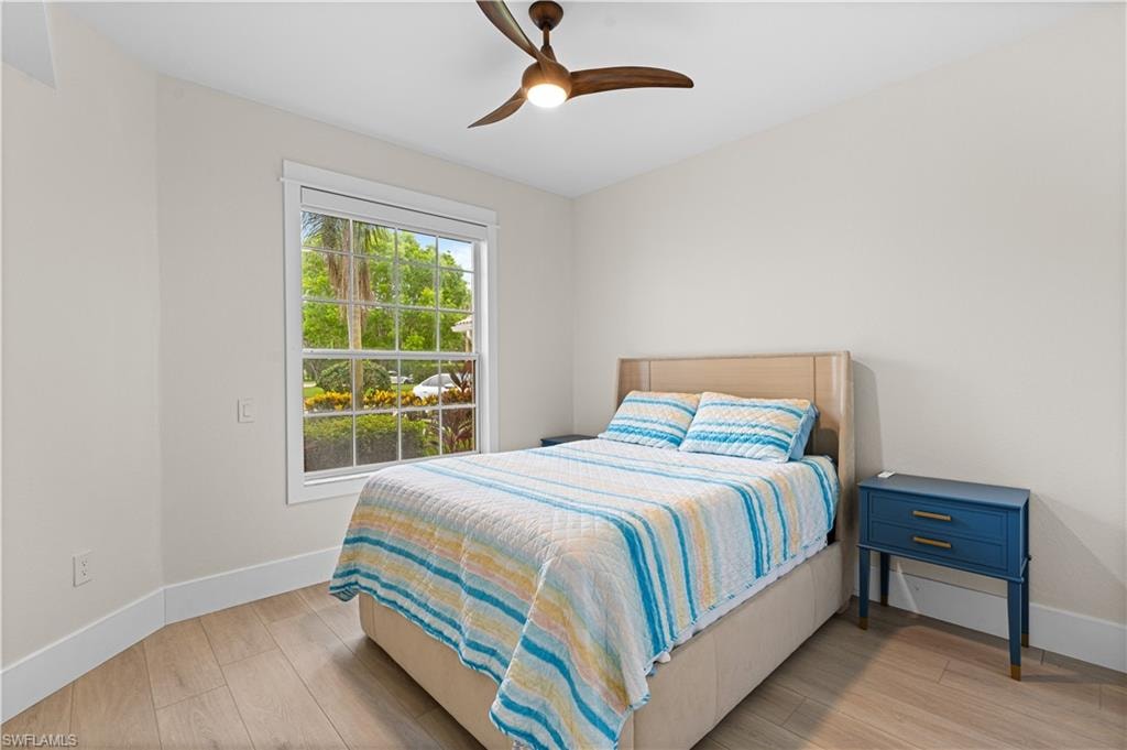 Bright room featuring light wood-finish flooring, a contemporary ceiling fan, and white baseboard trim