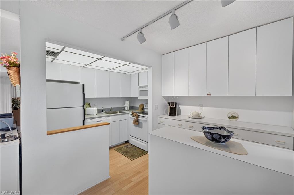 Kitchen featuring white cabinetry, track lighting, and wood-finish flooring