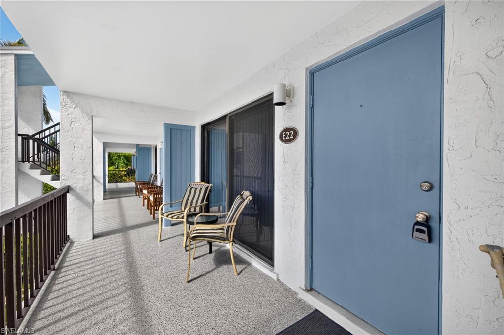 Covered exterior walkway featuring a textured ceiling, speckled flooring, and a blue entry door