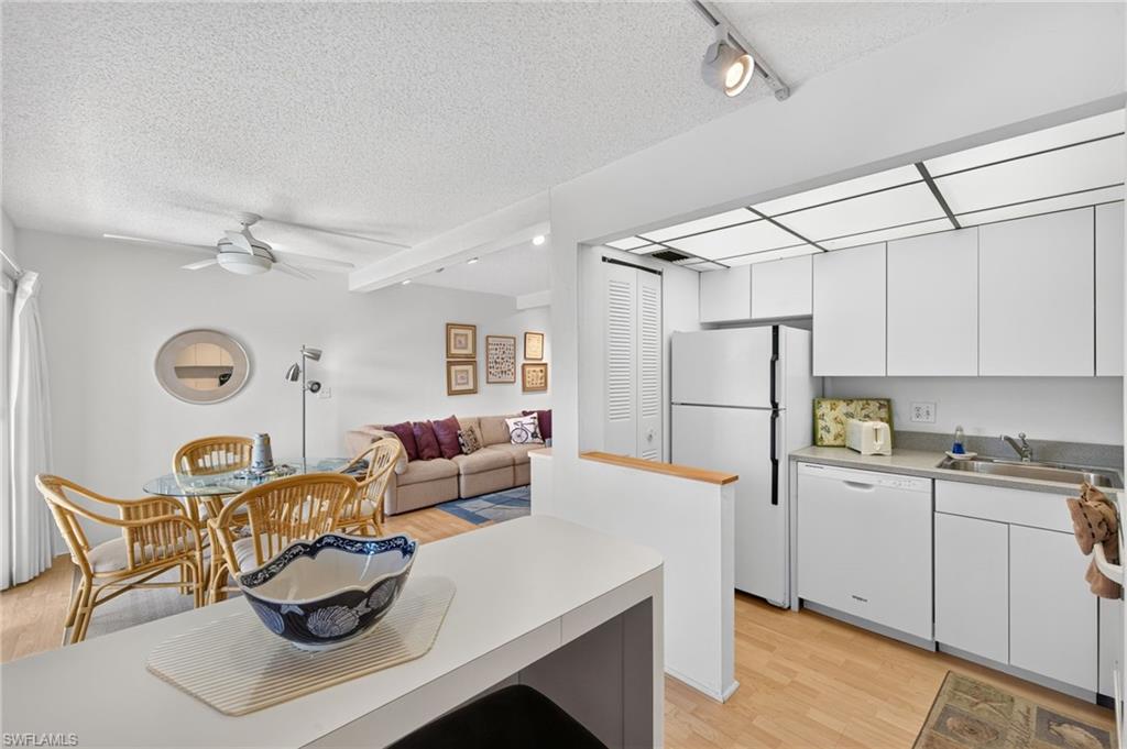 Kitchen with white cabinetry and appliances, wood-finish flooring, and track lighting